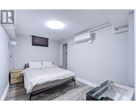 A bedroom with a bed, nightstand, and a wall-mounted air conditioner unit.