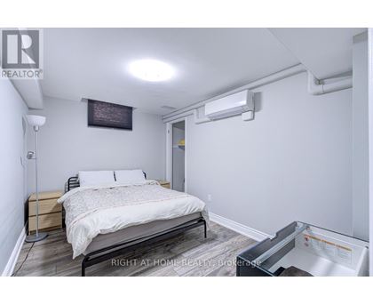 A bedroom with a bed, nightstand, and a wall-mounted air conditioner unit.