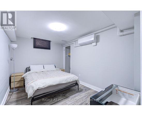 A bedroom with a bed, nightstand, and a wall-mounted air conditioner unit.