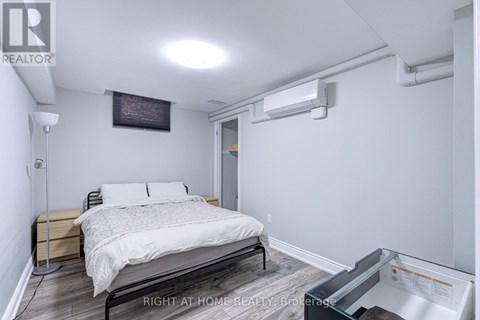 A bedroom with a bed, nightstand, and a wall-mounted air conditioner unit.