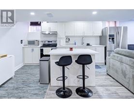 A kitchen with white cabinets and a white island with two black stools.