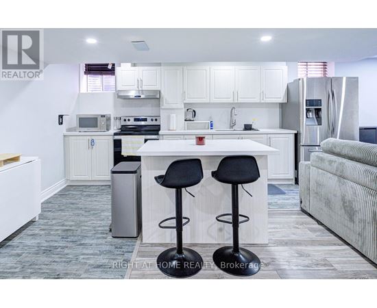 A kitchen with white cabinets and a white island with two black stools.