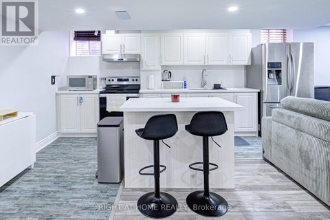 A kitchen with white cabinets and a white island with two black stools.