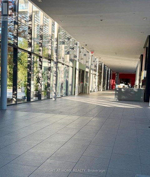 A long hallway with tiled floors and glass walls on one side.