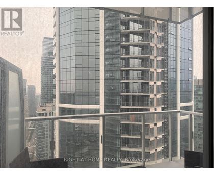 A modern glass building with a view of other buildings in the background.