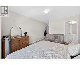 A bedroom with a white bed, a dresser, and a mirror.