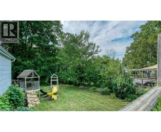 A backyard with a wooden deck and a play structure.