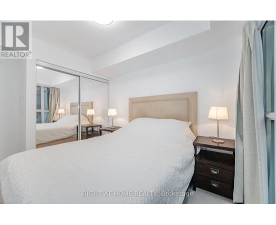 A bedroom with a large bed and a mirror on the wall.