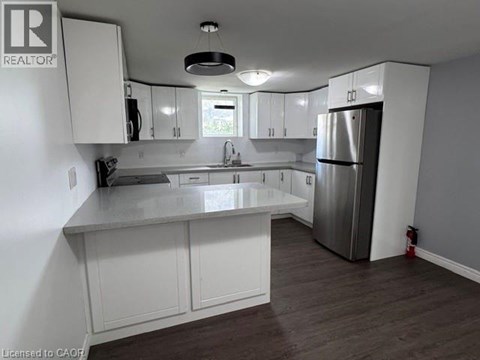 A kitchen with white cabinets and a stainless steel refrigerator.