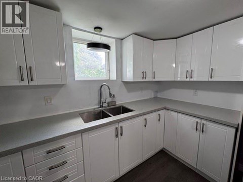 A kitchen with white cabinets and a window above the sink.