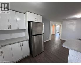 A kitchen with white cabinets and a stainless steel refrigerator.