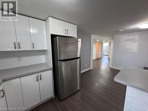 A kitchen with white cabinets and a stainless steel refrigerator.