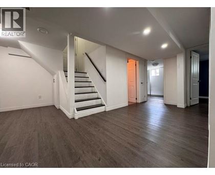 A spacious room with wooden floors and a staircase leading to another level.
