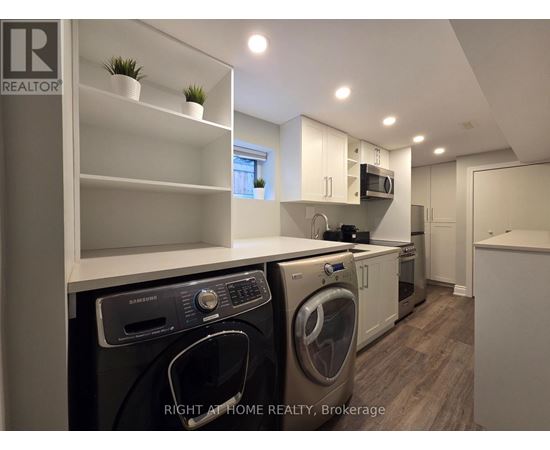 A modern kitchen with a washing machine and dryer built into the cabinetry.