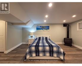 A bedroom with a bed, nightstand, and a painting on the wall.