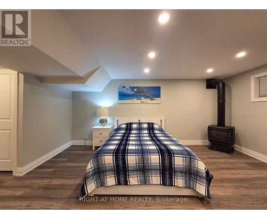 A bedroom with a bed, nightstand, and a painting on the wall.
