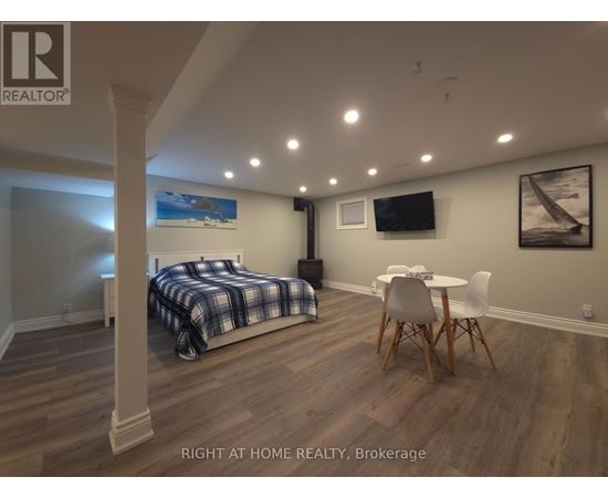 A bedroom with a bed, chair, and a painting on the wall.