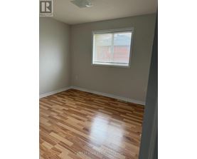 A room with wooden flooring and a window with blinds.