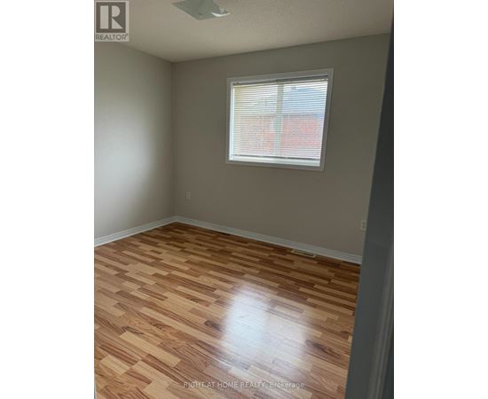 A room with wooden flooring and a window with blinds.
