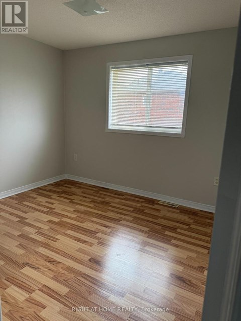 A room with wooden flooring and a window with blinds.