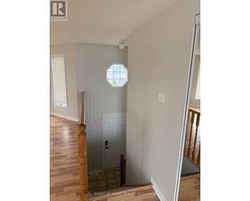 A white door is in a room with wooden floors and a window.