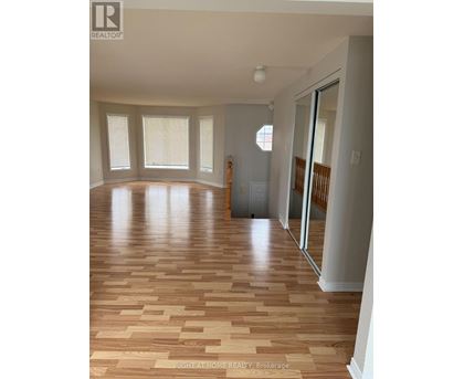 A room with wooden flooring and a door on the right side.