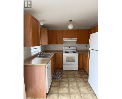 A kitchen with white appliances and wooden cabinets.