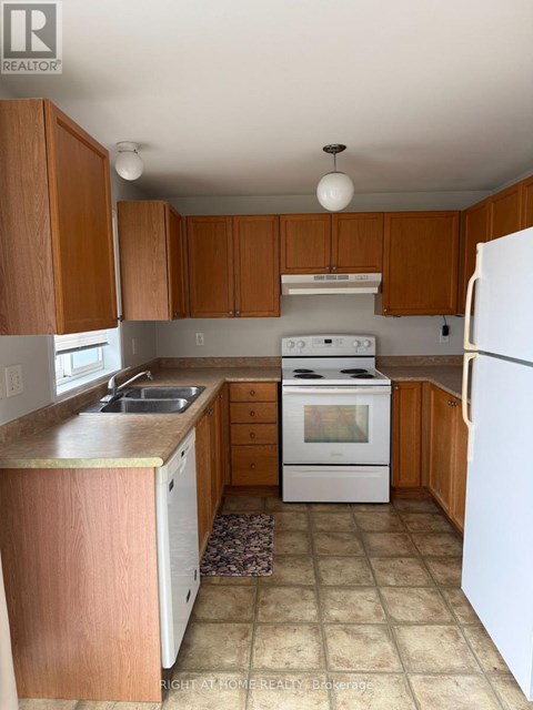 A kitchen with white appliances and wooden cabinets.