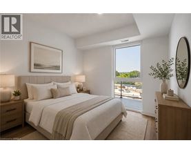 A bedroom with a large bed and a view of the outside through a sliding glass door.