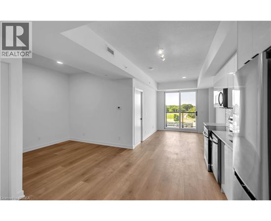 A spacious, empty room with wooden floors and white walls.