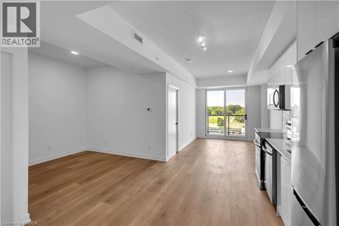 A spacious, empty room with wooden floors and white walls.