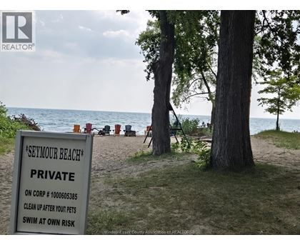 A sign on a beach reads "Seymour Beach Private" and instructs to clean up after pets and swim at own risk.
