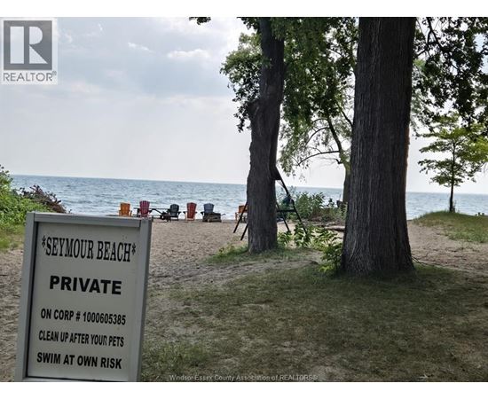 A sign on a beach reads "Seymour Beach Private" and instructs to clean up after pets and swim at own risk.