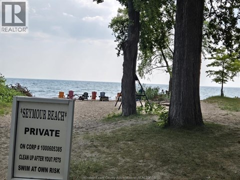 A sign on a beach reads "Seymour Beach Private" and instructs to clean up after pets and swim at own risk.