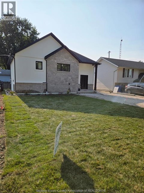A house with a white and brown exterior is surrounded by a green lawn.