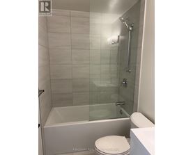 A white toilet sits next to a glass shower stall.