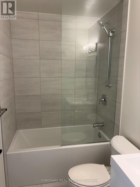 A white toilet sits next to a glass shower stall.