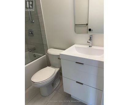 A white toilet sits next to a white sink in a bathroom.