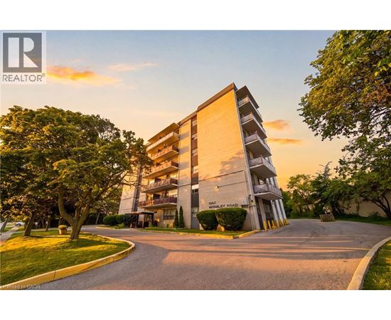 A modern apartment building with a driveway in front and trees on the side.
