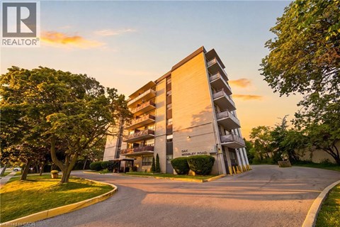 A modern apartment building with a driveway in front and trees on the side.