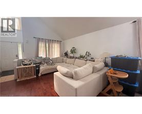 A living room with a white couch and a wooden stool.