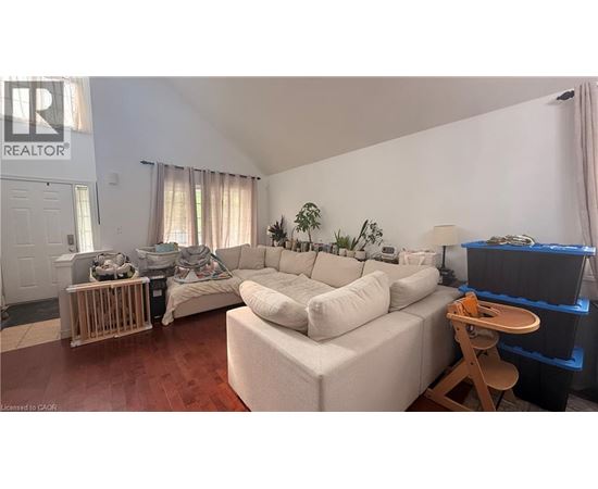 A living room with a white couch and a wooden stool.