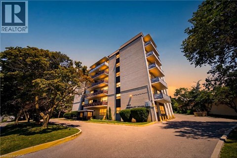 A modern apartment building with a well-maintained lawn and trees in front.