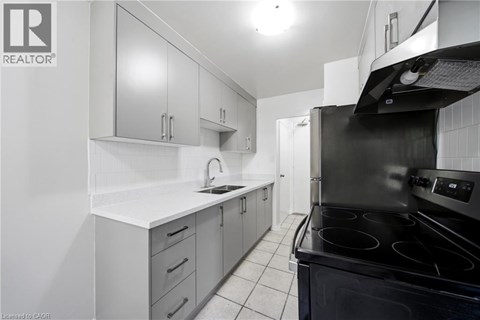 A modern kitchen with white cabinets and black appliances.