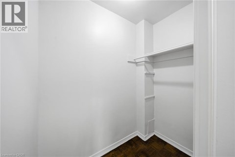 A white interior space with a shelf and a wooden floor.