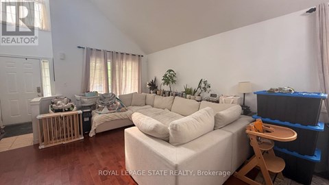 A living room with a white couch and a wooden stool.