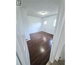 A room with wooden flooring and white walls.