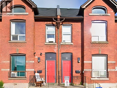 A red brick building with a red door and a sign that says "For Sale".