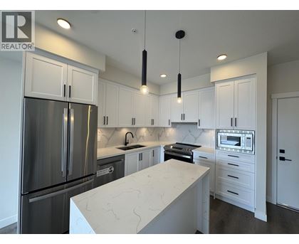 A modern kitchen with white cabinets and a marble island.