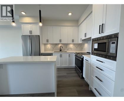 A modern kitchen with white cabinets and stainless steel appliances.